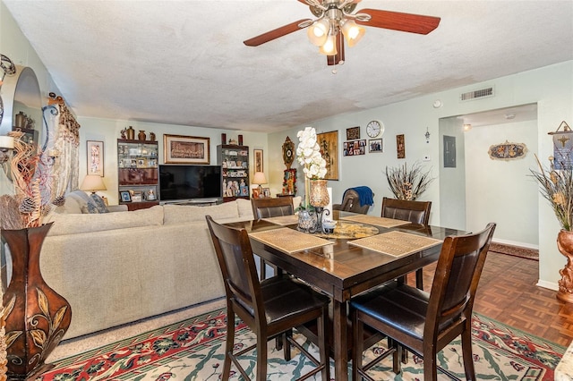 dining room with ceiling fan, dark parquet floors, and a textured ceiling