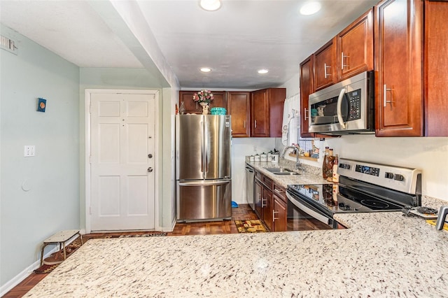 kitchen with light stone counters, sink, stainless steel appliances, and dark wood-type flooring