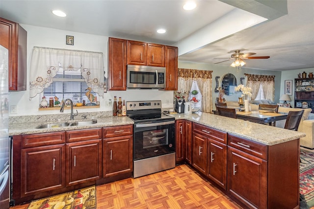 kitchen with kitchen peninsula, light stone counters, sink, and stainless steel appliances