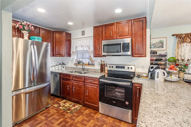 kitchen featuring dark parquet flooring, light stone counters, sink, and appliances with stainless steel finishes