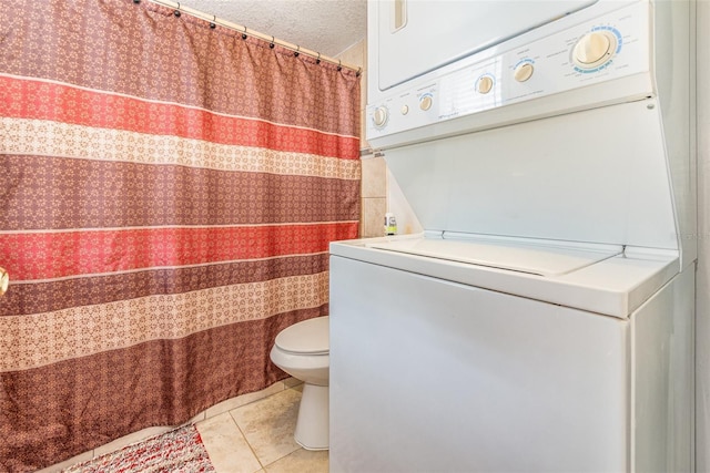 bathroom with tile patterned flooring, stacked washing maching and dryer, a textured ceiling, and toilet