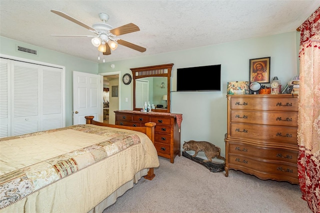 carpeted bedroom with a textured ceiling, a closet, and ceiling fan