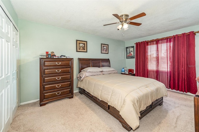 carpeted bedroom with a textured ceiling, a closet, and ceiling fan