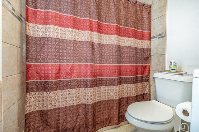 bathroom featuring toilet and tile walls