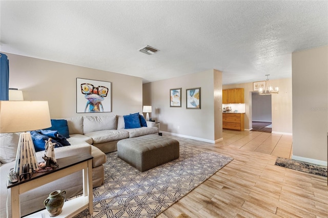 living room featuring light wood-type flooring, a textured ceiling, and a chandelier