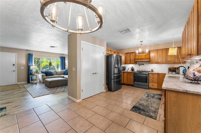 kitchen featuring an inviting chandelier, sink, a textured ceiling, appliances with stainless steel finishes, and decorative light fixtures