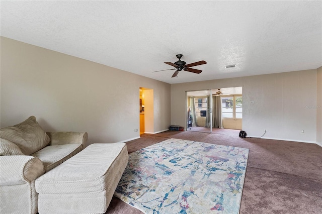 living room with carpet flooring, ceiling fan, and a textured ceiling