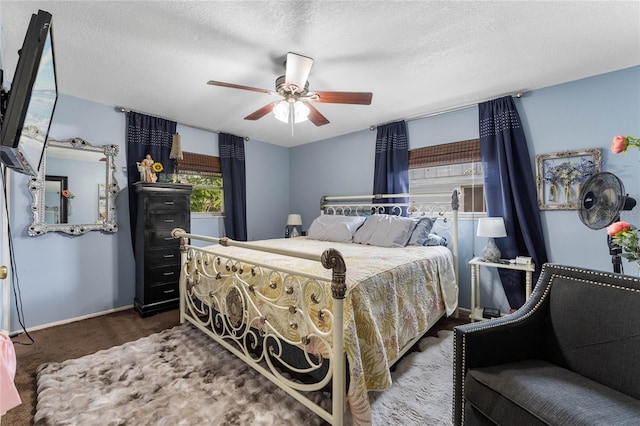 bedroom featuring a textured ceiling, dark carpet, and ceiling fan