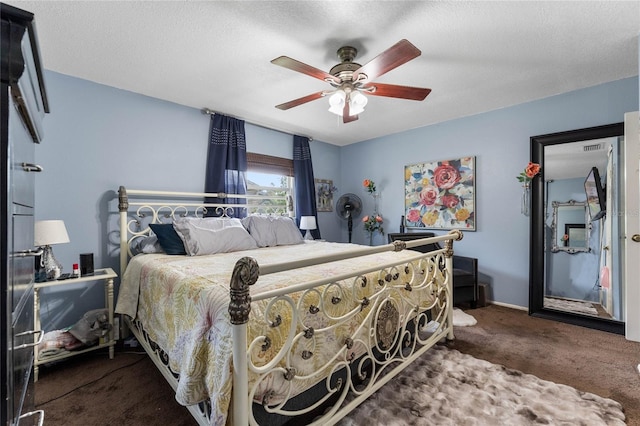 bedroom featuring dark colored carpet, ceiling fan, and a textured ceiling