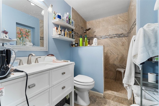 bathroom with vanity, toilet, and tiled shower