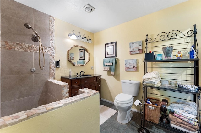 bathroom featuring vanity, toilet, and tiled shower