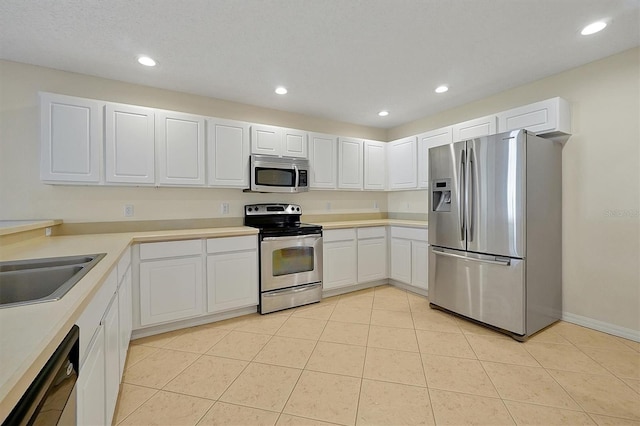 kitchen with appliances with stainless steel finishes, light tile patterned floors, and white cabinetry