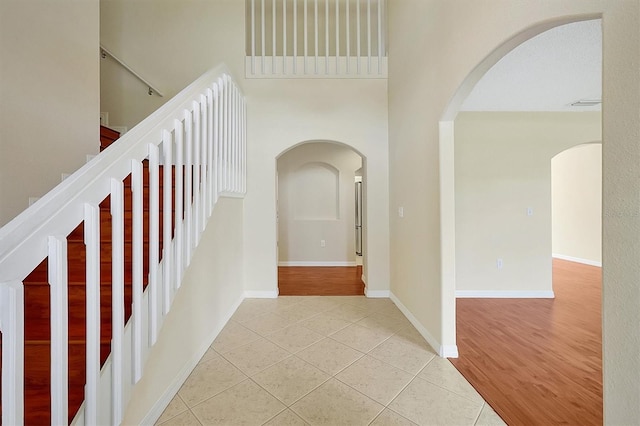 hall with a towering ceiling and light tile patterned flooring