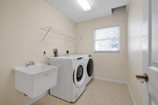 laundry room with separate washer and dryer, sink, light tile patterned flooring, and a textured ceiling