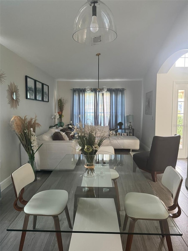 dining space with hardwood / wood-style floors and a notable chandelier