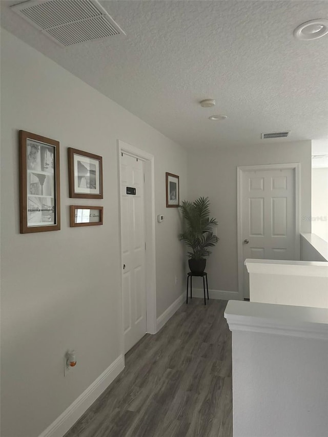 corridor with dark hardwood / wood-style flooring and a textured ceiling