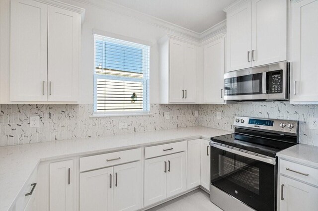 kitchen featuring light stone countertops, ornamental molding, appliances with stainless steel finishes, white cabinets, and decorative backsplash