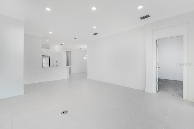 unfurnished living room with ornamental molding, sink, and light tile patterned floors