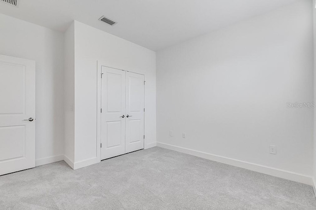 unfurnished bedroom featuring light carpet and a closet