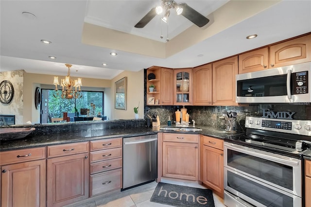 kitchen featuring backsplash, a raised ceiling, dark stone countertops, light tile patterned floors, and stainless steel appliances