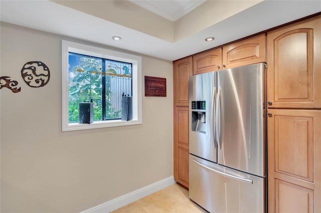 kitchen with stainless steel fridge, light tile patterned floors, and light brown cabinetry