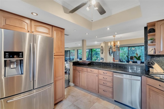 kitchen with stainless steel appliances, tasteful backsplash, a raised ceiling, dark stone countertops, and light tile patterned floors