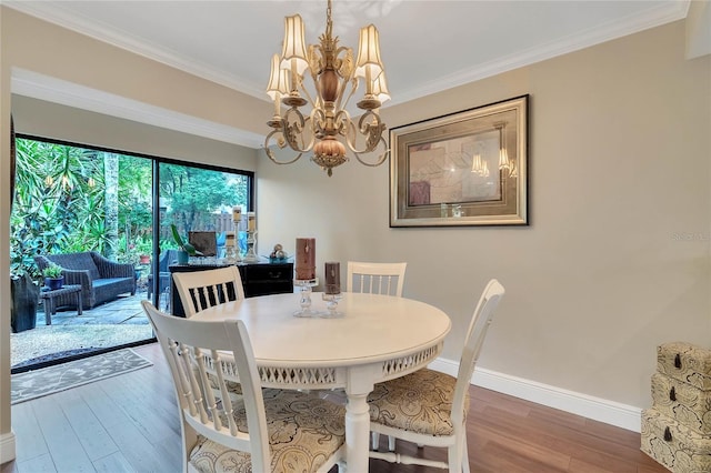 dining space with hardwood / wood-style flooring, crown molding, and a notable chandelier