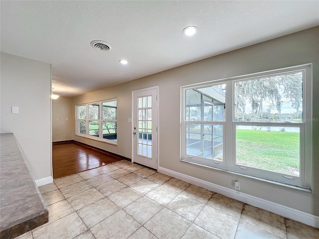 entryway featuring light tile patterned floors and a textured ceiling