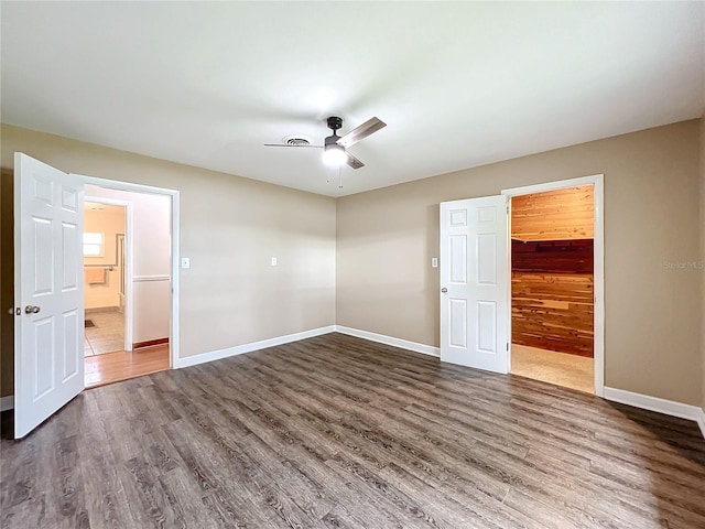 unfurnished bedroom featuring a spacious closet, dark hardwood / wood-style floors, ceiling fan, and a closet