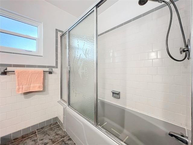 bathroom with tile patterned floors, bath / shower combo with glass door, and tile walls