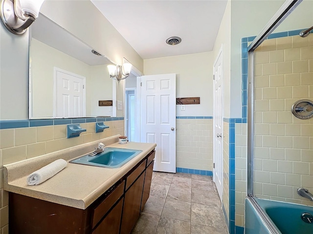 bathroom featuring tiled shower / bath, vanity, and tile walls