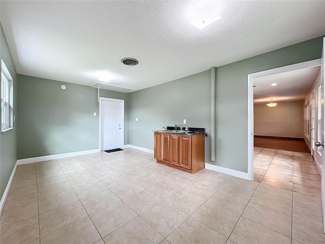 tiled empty room featuring sink and a textured ceiling