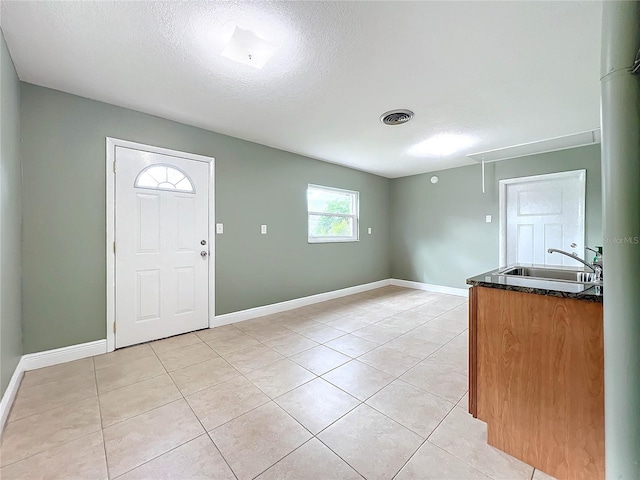 entryway featuring sink, a textured ceiling, and light tile patterned floors