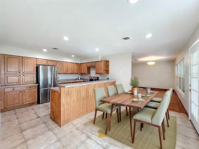 kitchen with freestanding refrigerator, visible vents, a peninsula, and recessed lighting