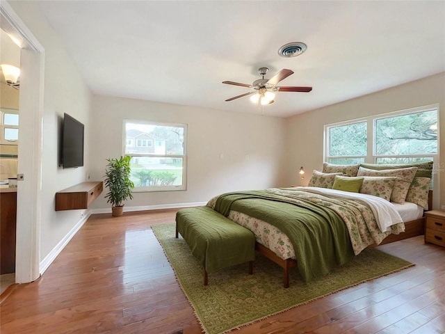 bedroom with hardwood / wood-style flooring, visible vents, multiple windows, and baseboards