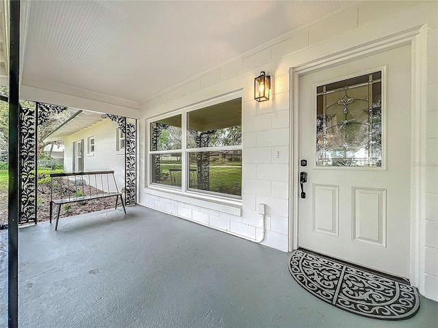 property entrance featuring a porch and concrete block siding