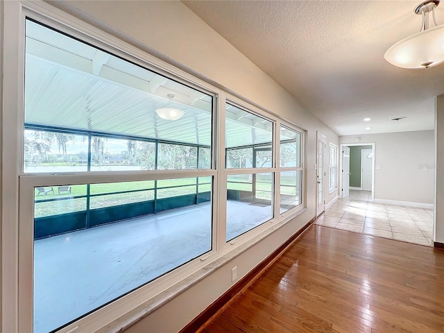 interior space featuring a healthy amount of sunlight, hardwood / wood-style flooring, baseboards, and a textured ceiling