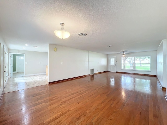 unfurnished room featuring visible vents, ceiling fan, light wood-style flooring, and a textured ceiling