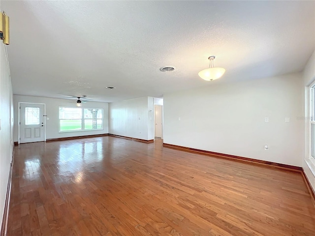 unfurnished room featuring baseboards, a textured ceiling, visible vents, and wood finished floors