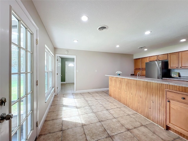 kitchen featuring recessed lighting, visible vents, baseboards, freestanding refrigerator, and brown cabinets