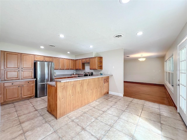 kitchen featuring freestanding refrigerator, visible vents, a peninsula, and open shelves