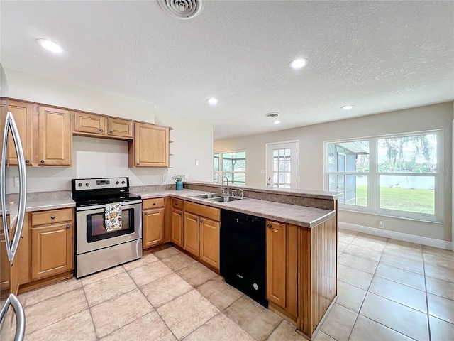 kitchen featuring a peninsula, a sink, visible vents, a healthy amount of sunlight, and appliances with stainless steel finishes