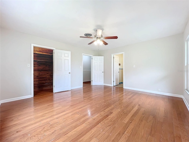 unfurnished bedroom with a spacious closet, light wood-style flooring, and baseboards