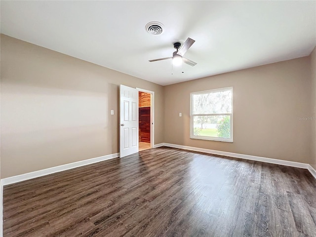 spare room featuring dark wood-type flooring, visible vents, baseboards, and a ceiling fan