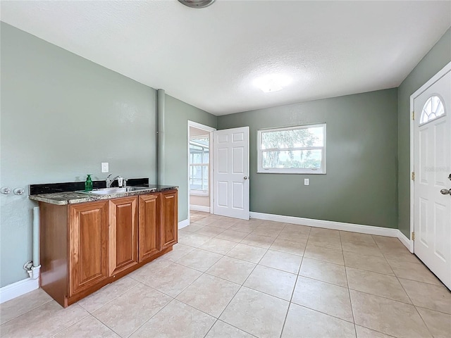 kitchen with light tile patterned floors, baseboards, and brown cabinets