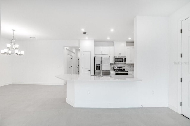 kitchen featuring hanging light fixtures, stainless steel appliances, backsplash, sink, and white cabinetry