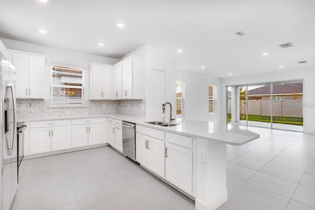 kitchen with sink, white cabinetry, dishwasher, a healthy amount of sunlight, and kitchen peninsula