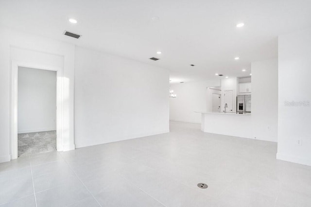 unfurnished living room with a chandelier and sink