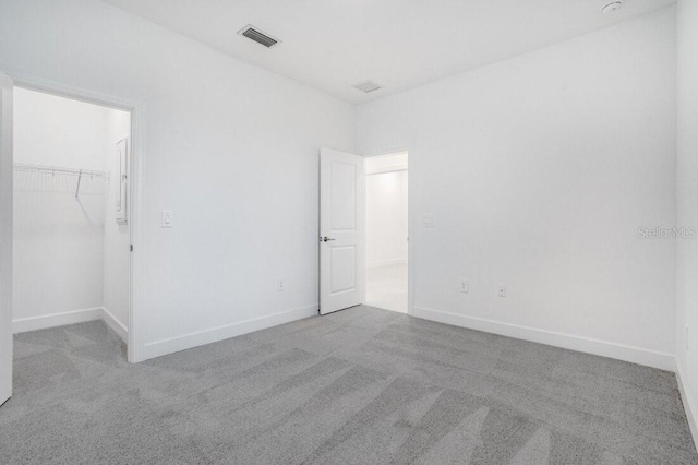 unfurnished bedroom with light carpet, a closet, and a spacious closet