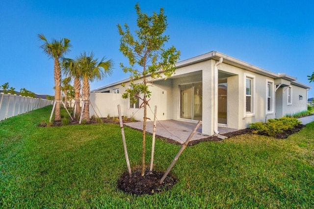 rear view of property with a patio and a lawn